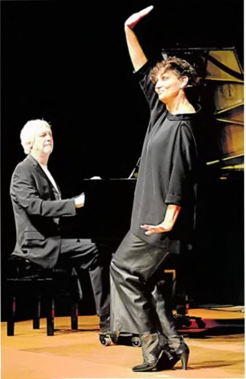 Sandra Kreisler mit erhobenem Arm auf der Bühne, dahinter Andreas Kohl am Flügel